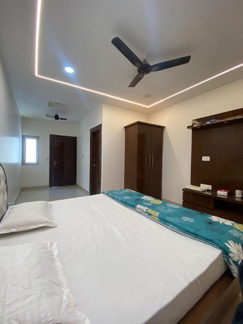 Comfortable hotel bedroom with ceiling fan, wooden wardrobe, and sleek design.