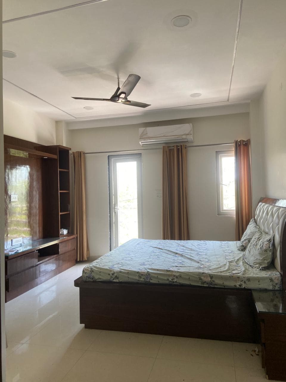 Relaxing bedroom with large bed, wooden furniture, and natural light from windows and balcony door.
