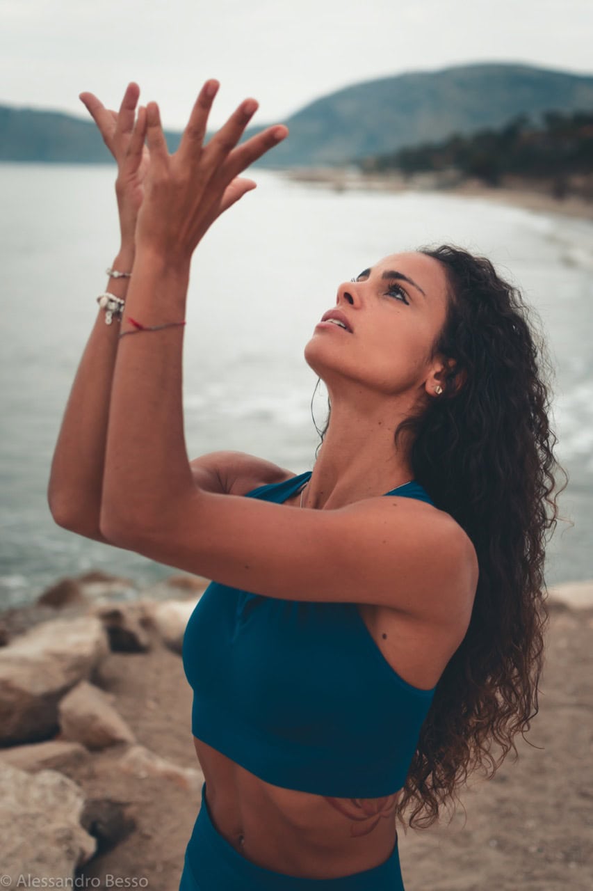 Yoga woman performing a pose by the water, emphasizing mindfulness and flexibility.