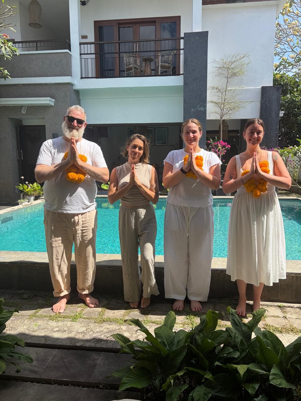 Group of four people practicing yoga outdoors by a pool at SVL Yoga.